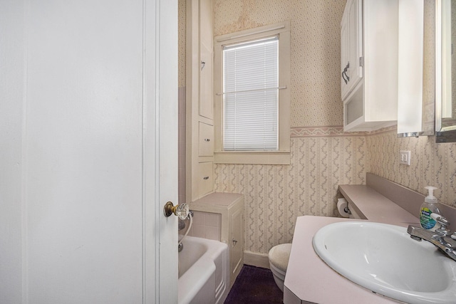 bathroom with vanity, toilet, and a tub