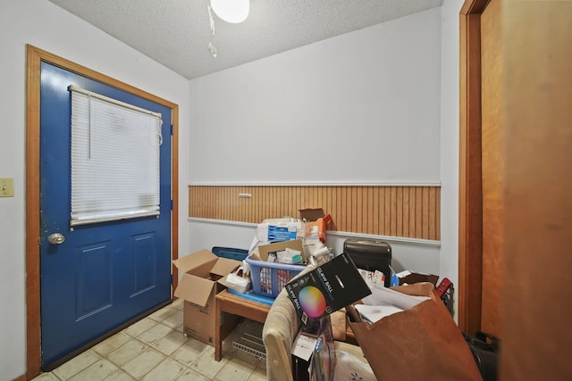 interior space with a textured ceiling and wooden walls