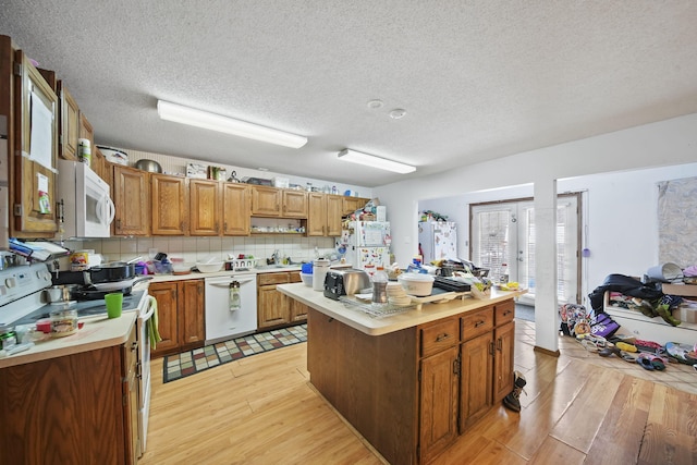 kitchen with white appliances, tasteful backsplash, a kitchen island, and light hardwood / wood-style floors