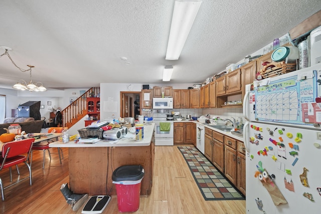 kitchen with hanging light fixtures, an inviting chandelier, white appliances, a kitchen bar, and a kitchen island