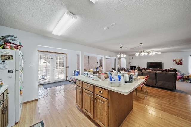 kitchen featuring white fridge, a kitchen island, hanging light fixtures, and light hardwood / wood-style flooring