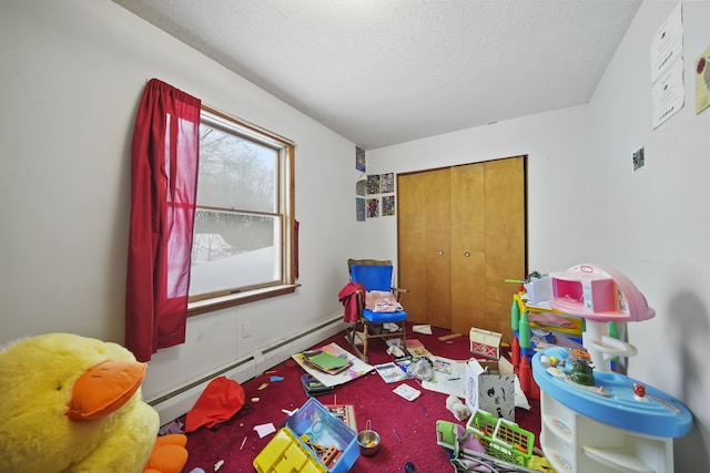 recreation room with a textured ceiling and a baseboard heating unit