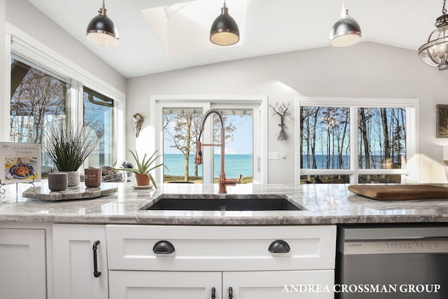 kitchen featuring lofted ceiling, a water view, sink, stainless steel dishwasher, and light stone counters