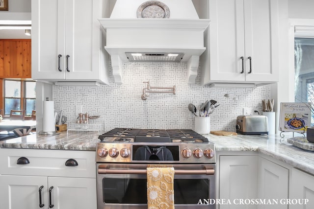 kitchen with backsplash, white cabinetry, and double oven range