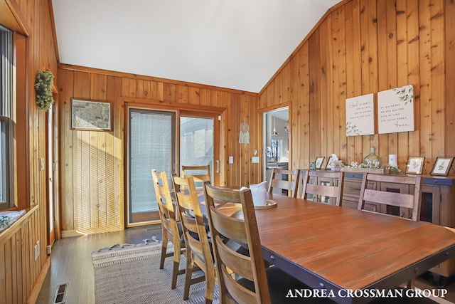 dining space featuring wooden walls, hardwood / wood-style floors, and lofted ceiling