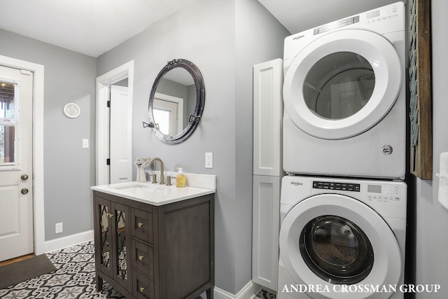 laundry area featuring cabinets, tile patterned floors, stacked washer / drying machine, and sink