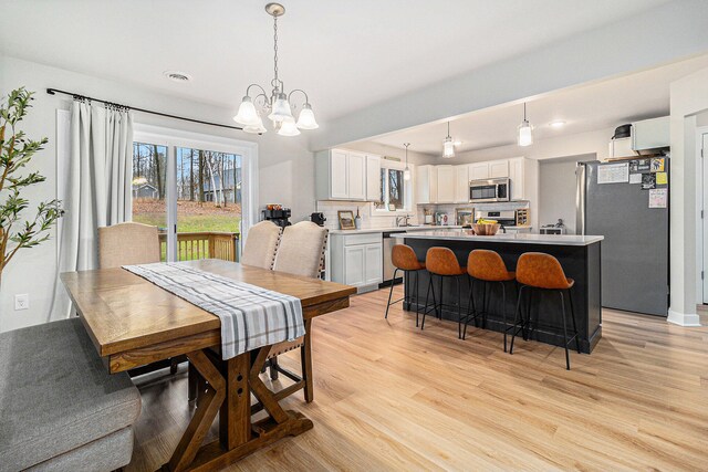 dining area featuring light hardwood / wood-style floors, a notable chandelier, and sink