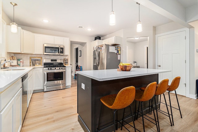 kitchen with appliances with stainless steel finishes, tasteful backsplash, sink, white cabinets, and a center island