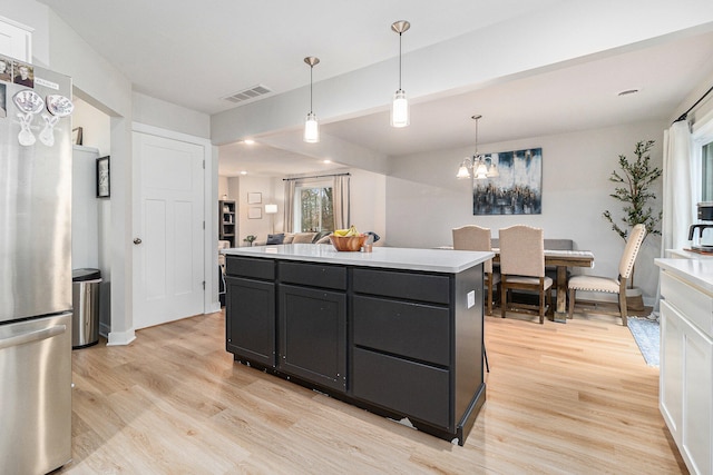 kitchen with stainless steel fridge, decorative light fixtures, a center island, and light hardwood / wood-style flooring