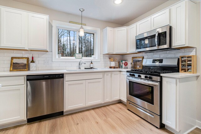 kitchen featuring white cabinets, decorative light fixtures, sink, and appliances with stainless steel finishes