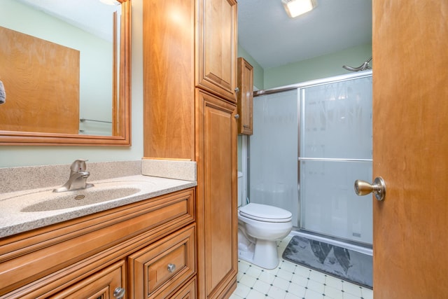 bathroom featuring tile patterned flooring, vanity, toilet, and a shower with shower door