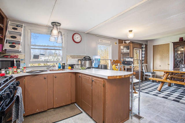 kitchen featuring kitchen peninsula, black range with gas stovetop, and decorative light fixtures