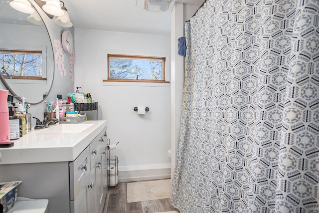 bathroom with a wealth of natural light, hardwood / wood-style floors, vanity, and toilet