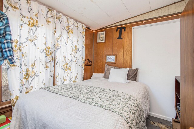 bedroom featuring hardwood / wood-style floors, wooden walls, and lofted ceiling