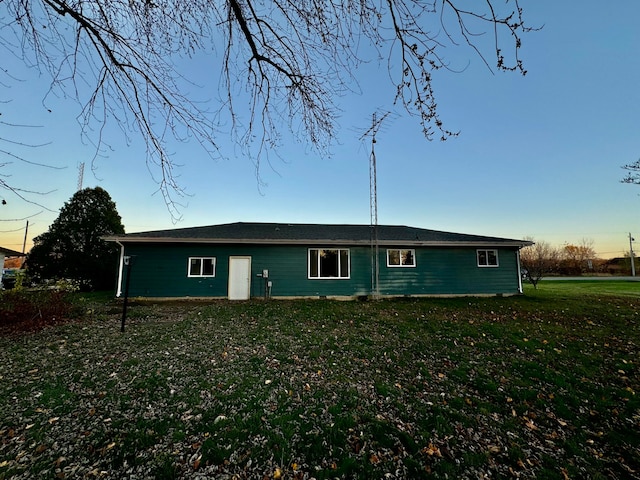 back house at dusk with a lawn