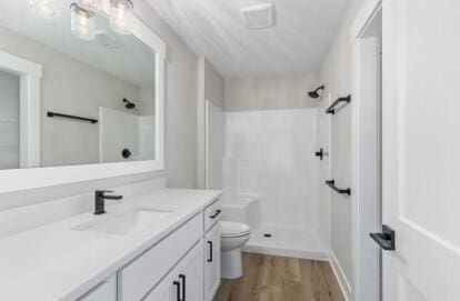 bathroom with a shower, vanity, wood-type flooring, and toilet