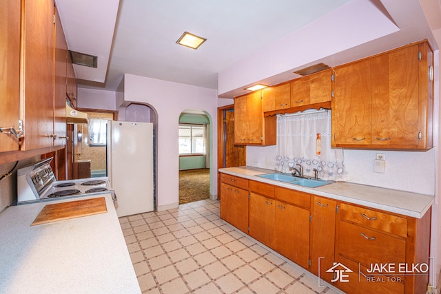 kitchen with white refrigerator, premium range hood, sink, and electric range oven