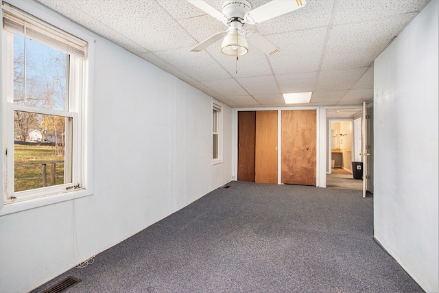 carpeted empty room featuring a drop ceiling and ceiling fan