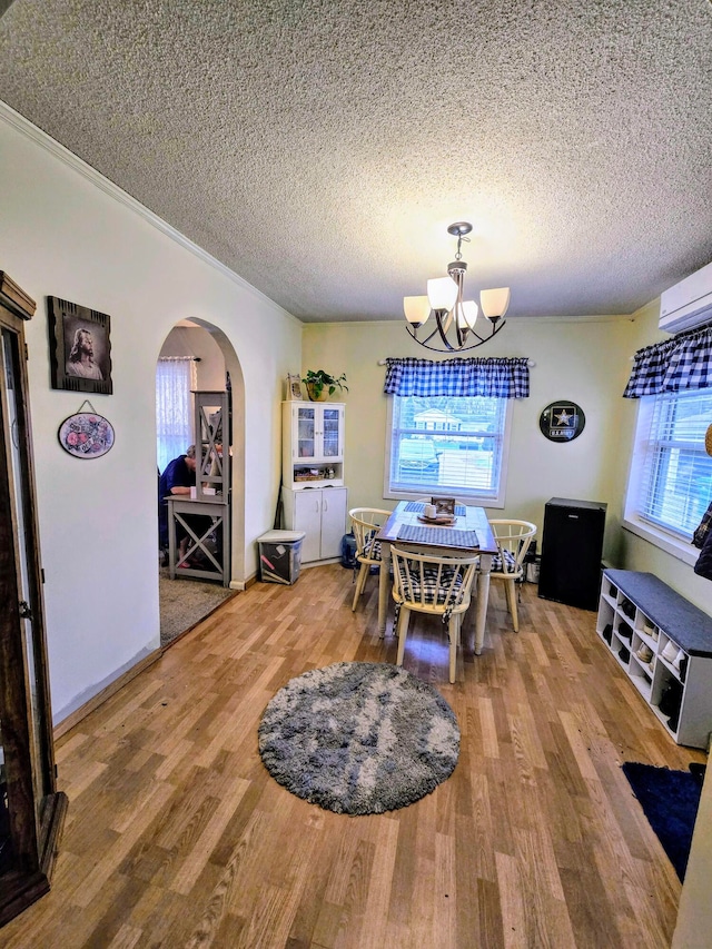 dining area with wood-type flooring, a textured ceiling, and an inviting chandelier