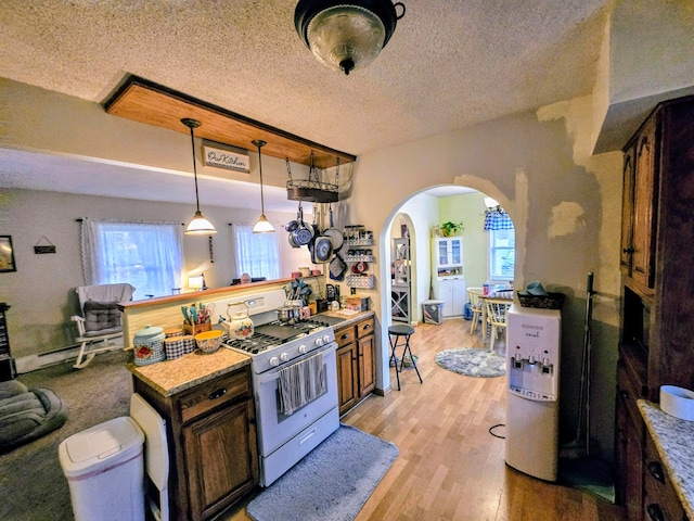 kitchen with light wood-type flooring, stainless steel range, dark brown cabinets, a textured ceiling, and pendant lighting