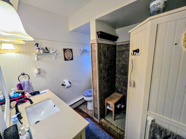 bathroom with tiled shower, wooden walls, baseboard heating, and toilet