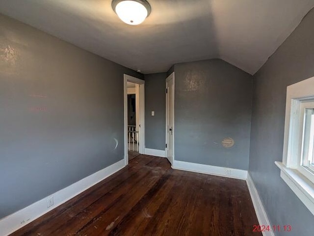 unfurnished room with dark hardwood / wood-style flooring and lofted ceiling