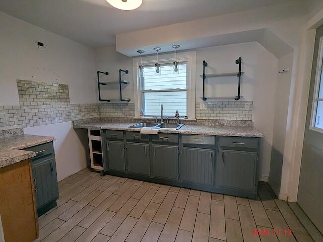 kitchen with backsplash, decorative light fixtures, light hardwood / wood-style flooring, and sink