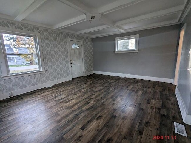 spare room featuring beam ceiling, dark hardwood / wood-style flooring, and plenty of natural light