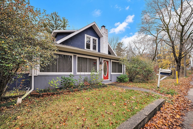 view of front of property featuring a sunroom and a front lawn