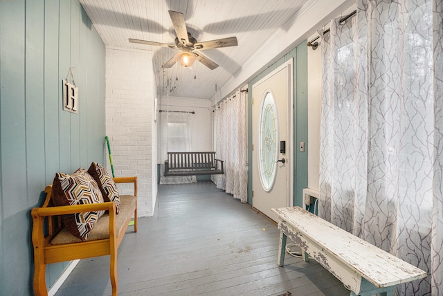 foyer featuring wood-type flooring, ceiling fan, wood walls, and brick wall