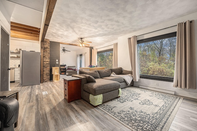 living room with a textured ceiling, hardwood / wood-style flooring, ceiling fan, and a healthy amount of sunlight