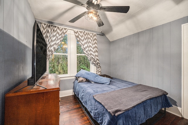 bedroom with wood walls, ceiling fan, dark hardwood / wood-style floors, and lofted ceiling