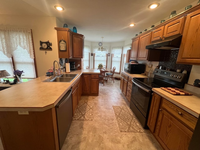 kitchen with kitchen peninsula, sink, black appliances, pendant lighting, and a chandelier