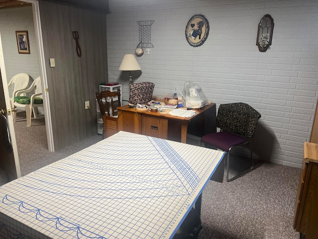 carpeted home office featuring brick wall