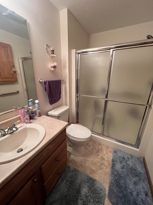 bathroom with tile patterned floors, an enclosed shower, vanity, a textured ceiling, and toilet