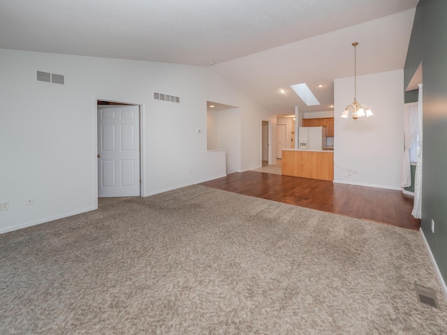 unfurnished living room with light hardwood / wood-style floors, an inviting chandelier, and vaulted ceiling with skylight