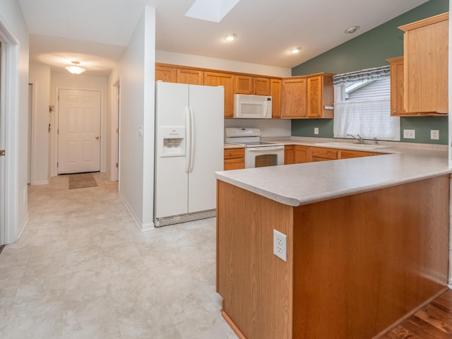 kitchen featuring sink, white appliances, kitchen peninsula, and vaulted ceiling with skylight