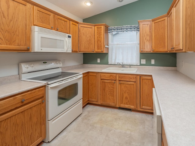 kitchen featuring lofted ceiling, white appliances, and sink