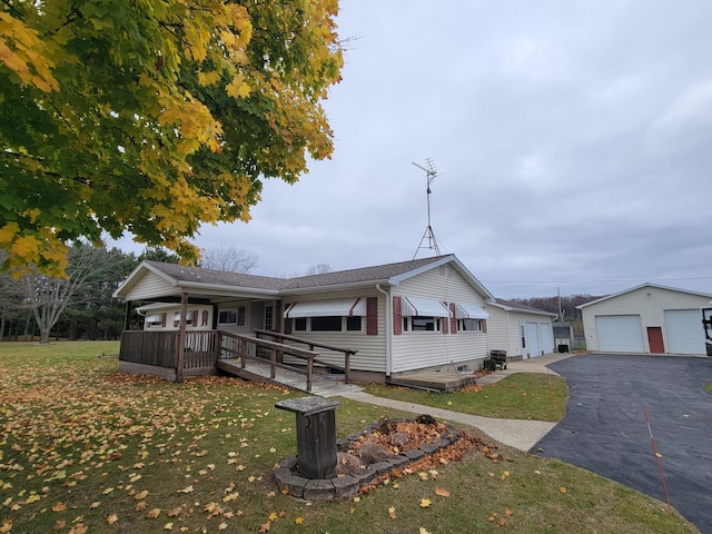 view of front of property featuring a front yard, a deck, a garage, and an outdoor structure