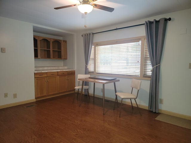 unfurnished dining area featuring ceiling fan and dark wood-type flooring