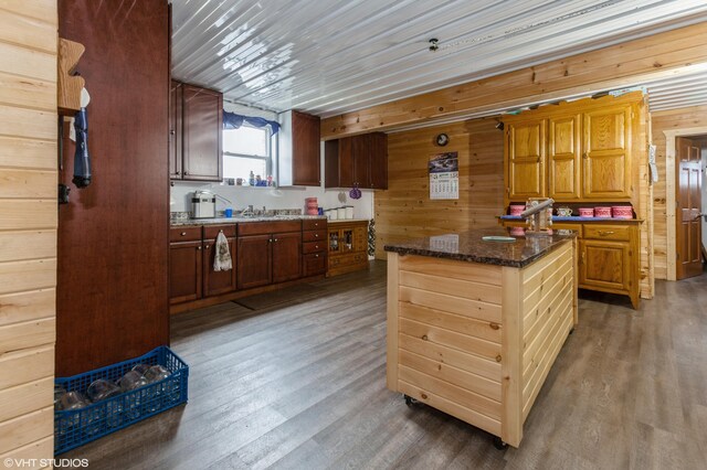 kitchen featuring dark stone countertops, wood walls, and dark hardwood / wood-style flooring