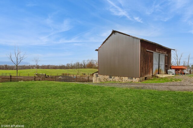 view of outbuilding featuring a rural view and a lawn