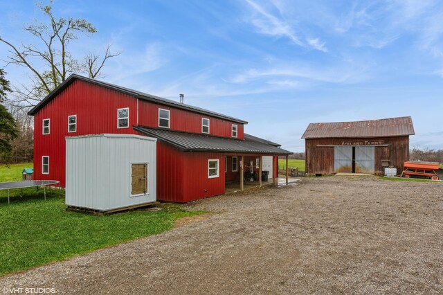 rear view of house with an outbuilding and a trampoline