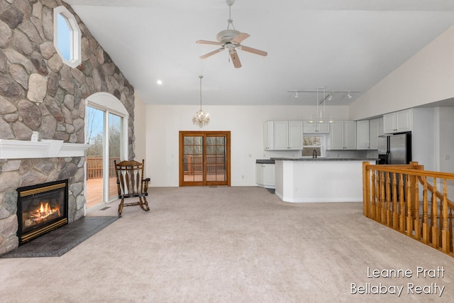 carpeted living room featuring high vaulted ceiling, track lighting, sink, ceiling fan, and a fireplace