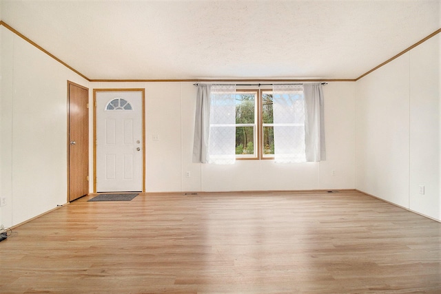 empty room with light hardwood / wood-style flooring, a textured ceiling, and ornamental molding