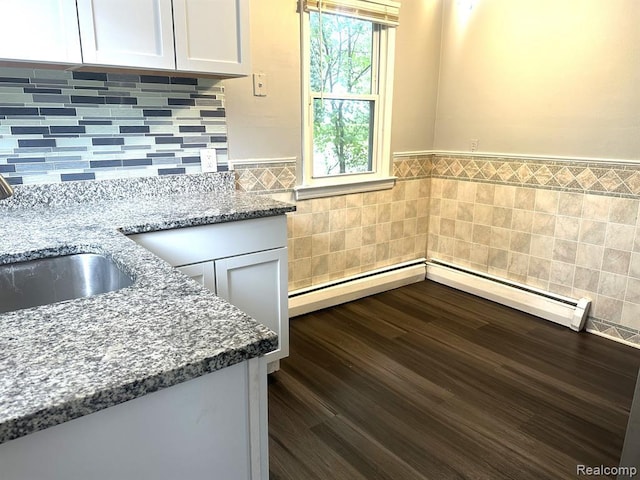 kitchen with white cabinetry, sink, dark wood-type flooring, baseboard heating, and stone countertops