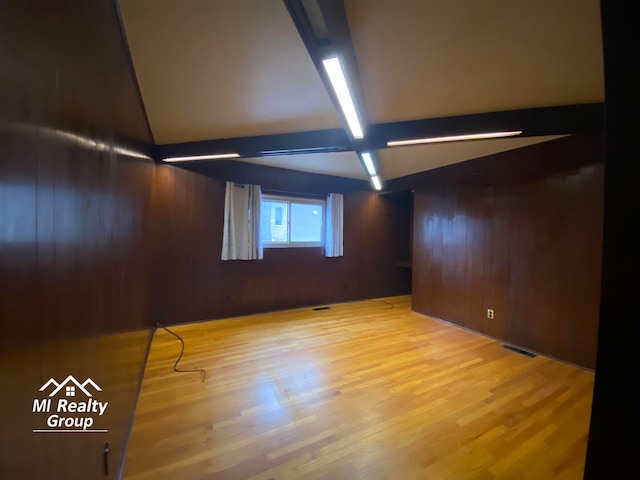 basement with light hardwood / wood-style flooring and wood walls