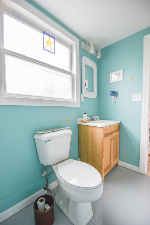 bathroom with vanity, toilet, and concrete floors