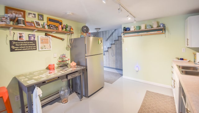 kitchen with stainless steel fridge, sink, white cabinets, and track lighting