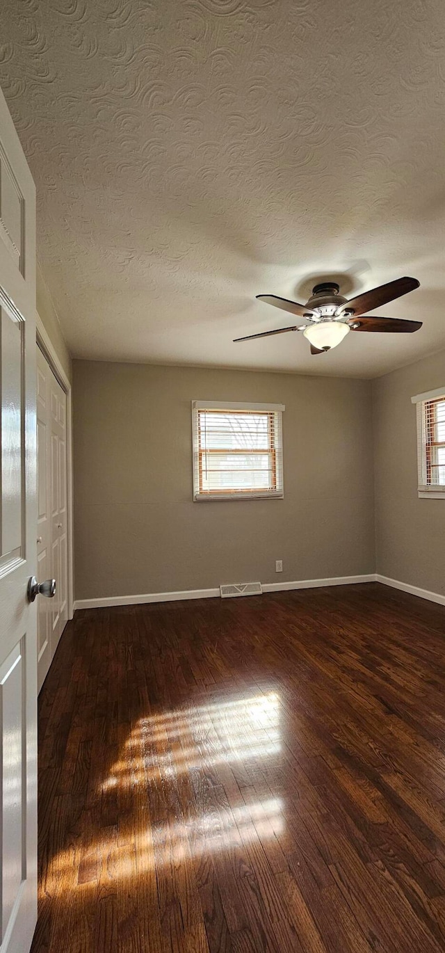 unfurnished room featuring dark hardwood / wood-style flooring, plenty of natural light, and a textured ceiling